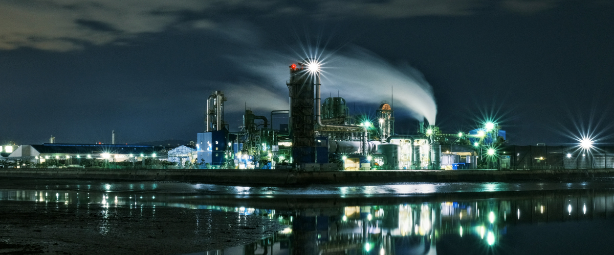 Industrial plant at night with lights reflecting on water