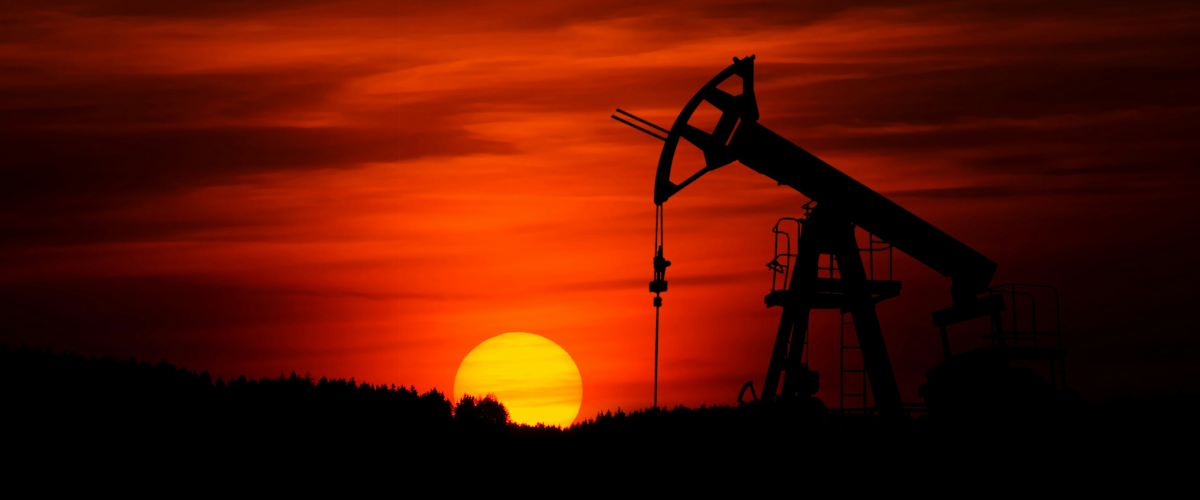 Silhouette of an oil pumpjack against a fiery sunset sky
